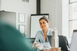 © Maskot - Portrait of smiling young businesswoman sitting at desk in tech startup office