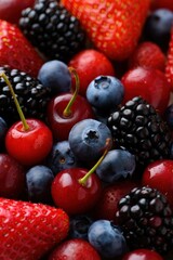 Poster - A close-up view of fresh berries in various shades of red, blue, and black, with green stems and leaves, suggesting they are ripe and ready to eat.