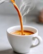 © MarinkaLev - Stream of espresso pouring into a white ceramic cup, steam rising, smooth swirl in motion, minimal background