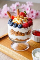 Aufkleber - A glass bowl filled with ice cream, fruit, whipped cream, and nuts on a wooden cutting board.