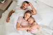 © Pixel-Shot - Happy parents with their little daughter lying under blanket in bedroom, top view