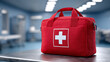 © SAN - A red first aid kit with a white cross sits on a table inside a modern medical facility.