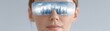 © Sasiwan - A woman wears futuristic glasses reflecting a digital cityscape, symbolizing virtual reality and advanced technology.