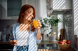© Drazen - Happy woman drinking orange juice in kitchen.