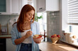 © Drazen - Smiling woman having healthy breakfast in kitchen.