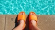 © Candra - AI image of a person's feet wearing bright orange slide sandals at the edge of a sparkling blue swimming pool.