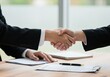 © Vooglo.com - Close-up of two business people shaking hands over a contract on a wooden desk in a bright office