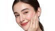 © VisionCrafter - Close-up portrait of a smiling young woman with clear skin touching her face, natural makeup, and relaxed expression on a plain white background