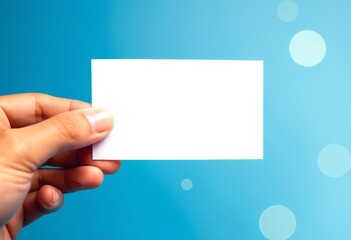 Fototapete - A hand holds a blank white card against a blue background with soft circular light effects