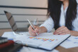 © crizzystudio - Businesswoman analyzing financial chart with pen and laptop