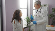 © Krakenimages.com - Doctor consulting woman in clinic office with plants and shelves behind, emphasizing healthcare discussion in professional setting highlighting medical interaction