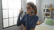 © Krakenimages.com - Woman exercising indoors with dumbbells in cozy bedroom setting, showcasing fitness and strength as she lifts weights under soft natural light from large window.
