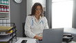© Krakenimages.com - Woman doctor in hospital clinic wearing glasses and white coat working on laptop in office environment providing medical care during daytime indoors.