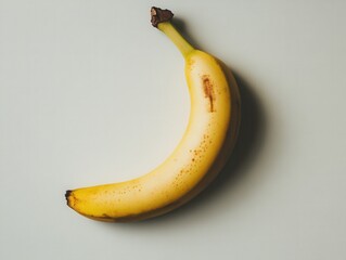 Poster - Studio shot of single ripe banana on light background showing natural imperfections and shadow from above for healthy eating concept