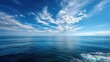 © Suphawan - Expansive ocean view with the horizon in the distance, featuring a bright blue sky and a slight breeze making small ripples on the water