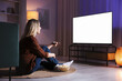 © New Africa - Woman with popcorn watching tv at home in evening
