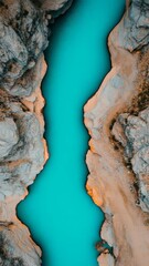 Poster - Turquoise water flows gracefully between rugged, rocky cliffs, creating a breathtaking natural canyon, captured from an aerial perspective showcasing the beauty and power of nature
