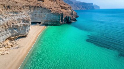 Poster - Aerial view capturing crystal clear turquoise water washing onto a pristine sandy beach beneath towering rugged cliffs, showcasing tranquil beauty in musandam, oman