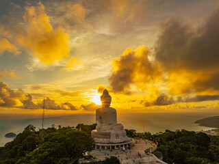 Wall Mural - A breathtaking aerial view of the iconic Big Buddha statue overlooking the Andaman Sea in Phuket, Thailand, captured during a vibrant sunset. The golden sky reflects on the water. beautiful sunset