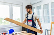 © Mediteraneo - A young man works diligently on renovating his apartment, focusing on the installation of laminate flooring.