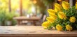 © Maryna - Empty wooden table in front of spring mimosa flowers banner. Rustic wooden tabletop with blurred bokeh background for product display in a coffee shop or market. Yellow flowers, sunlight, spring mood.