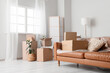 © Pixel-Shot - Brown sofa with film and cardboard boxes in room on moving day