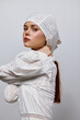 © SHOTPRIME STUDIO - Young woman in a white embroidered dress and headscarf, expressing confidence and elegance in a minimalist studio setting with a soft color palette