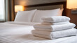 © Jhati - Luxurious hotel room featuring neatly stacked towels on a pristine bed in a serene setting