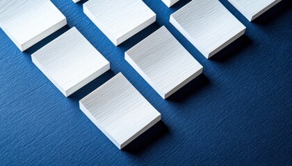 Poster - Close up of textured white blocks arranged diagonally against a dark blue speckled surface. The high angle emphasizes geometric patterns and contrasting textures