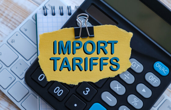 A calculator sits on a desk with a piece of paper that says Import Tariffs on