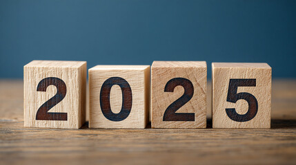 Fototapete - Wooden blocks displaying 2025 on a wood surface against a blue background, symbolizing the upcoming year and new beginnings