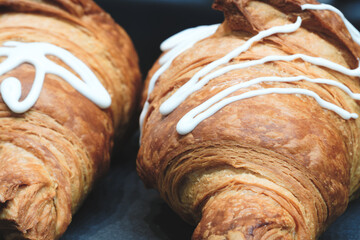 Poster - Two croissants with white frosting on them. The frosting is in a zigzag pattern.