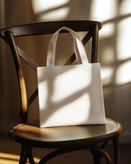 Poster - White tote bag mockup on wooden chair in sunlight studio shot for branding design presentation shopping eco friendly lifestyle