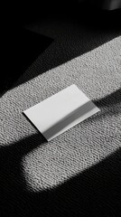 Aufkleber - Blank white card resting on gray carpet in sunlight shadow top view minimal style indoor setting