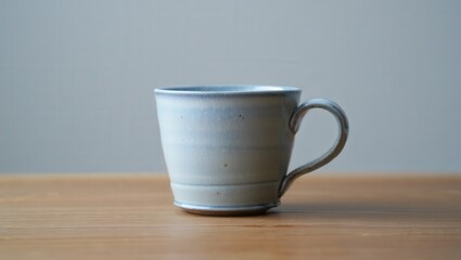 Poster - A blue ceramic coffee cup on a wooden table.