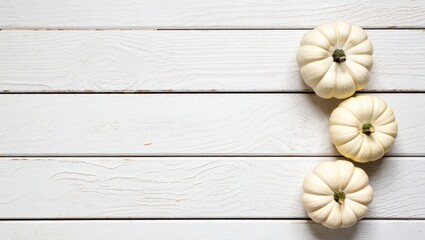 Poster - Three pumpkins on a white wooden surface.