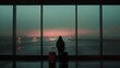 © Sirichat. Camphol - A person standing at an airport window, looking at the runway while holding onto their suitcase,