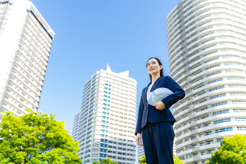 Aufkleber - 新緑の街の前にヘルメットを持って立つ女性ビジネスパーソン