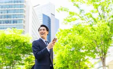 Poster - 新緑の街でスマホを使う男性ビジネスパーソン