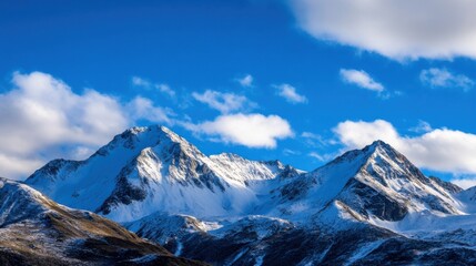 Aufkleber - Majestic snow-capped mountain range under a vibrant blue sky, with fluffy white clouds partially obscuring the peaks, creating a serene winter landscape. : Generative AI