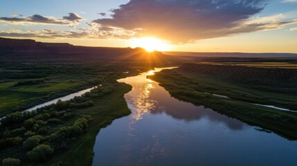 Aufkleber - Sunset over a meandering river in a canyon landscape, reflecting golden light on calm water, surrounded by lush green vegetation and red rock formations. : Generative AI