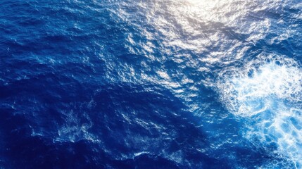 Aufkleber - Aerial view of deep blue ocean water with sunlight reflecting on the surface and whitecaps forming near the bottom right corner. : Generative AI