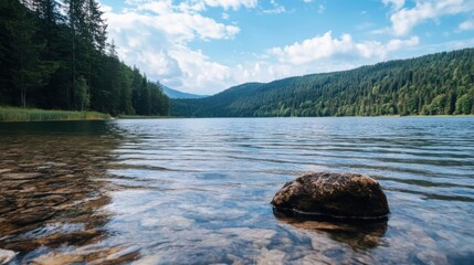 Leinwandbilder - Serene mountain lake scene with crystal-clear water, a single rock in the foreground, and a lush green forest backdrop under a partly cloudy sky. : Generative AI