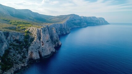 Poster - Aerial view of dramatic coastal cliffs meeting a deep blue sea under a partly cloudy sky, showcasing rugged terrain and tranquil waters. : Generative AI