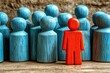 © Worrapol - Unique Red Figure Standing Out Among Many Blue Wooden Figures Representing Individuality and Distinction in Groups or Communities