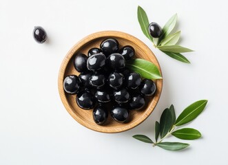 Aufkleber - A wooden bowl filled with glistening black olives, surrounded by fresh olive leaves on a white background.  The olives are plump and appear juicy, ready to eat. : Generative AI