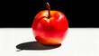 © wildan - A vibrant red apple sits on a stark white surface against a black backdrop, casting a defined shadow