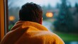 © DYAH - A person wrapped in a blanket gazes out of a window at the rainy outdoors
