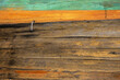 © Dina - A closeup of the aged weathered wooden side of a boat with worn textures and painted green, yellow and orange trim.