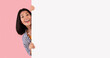 © Prostock-studio - Intresting Offer. Happy Casual Asian Woman Peeping Out The Side Of White Advertisement Board For Your Text Or Design. Smiling Lady Holding Billboard, Looking At Camera, Standing Over Pink Wall